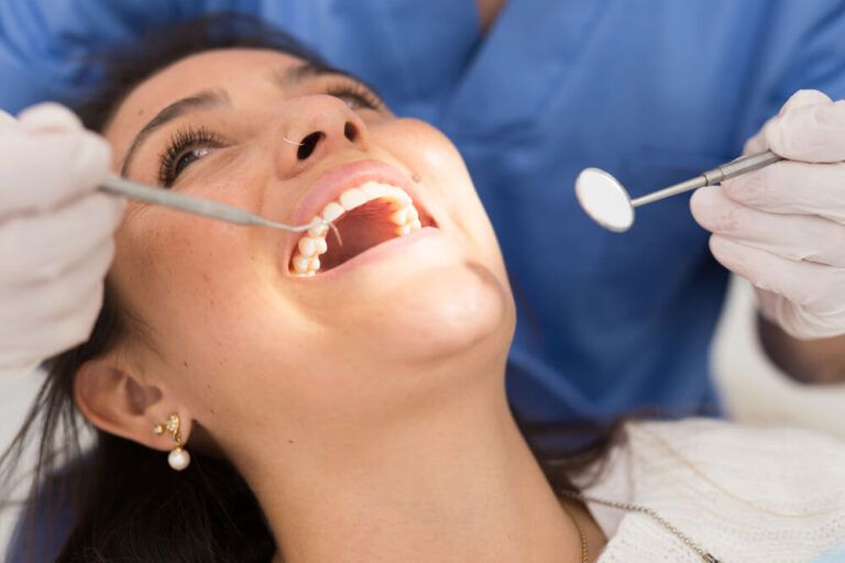 dentist treating teeth of woman in dentist office