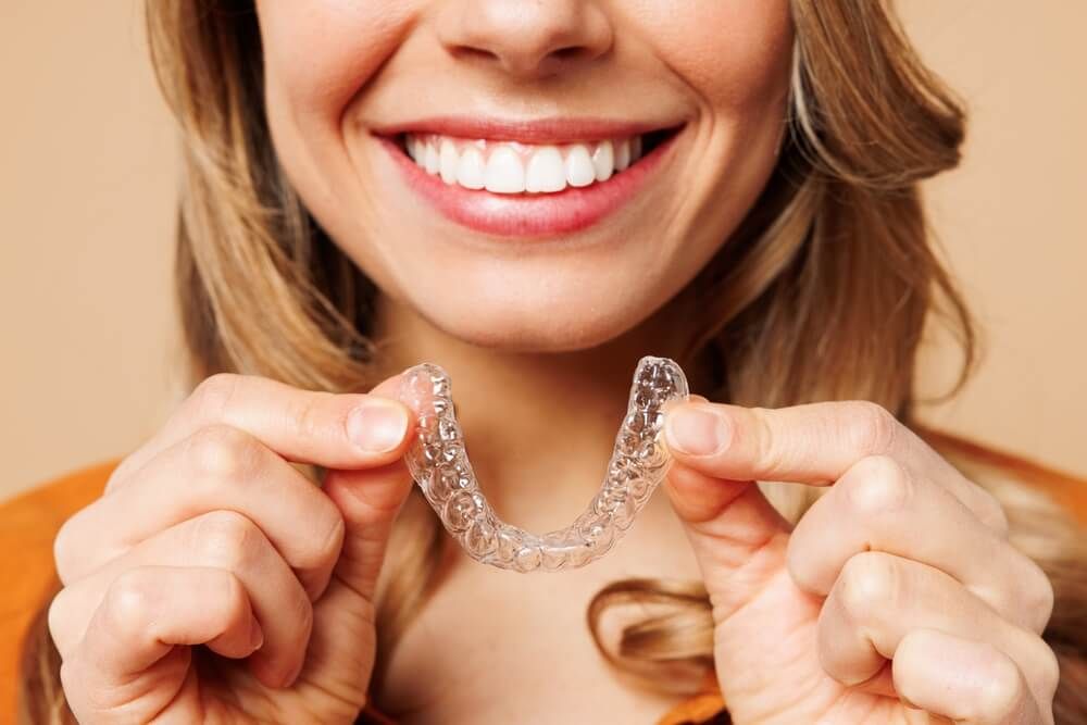 young woman holding invisible transparent aligners