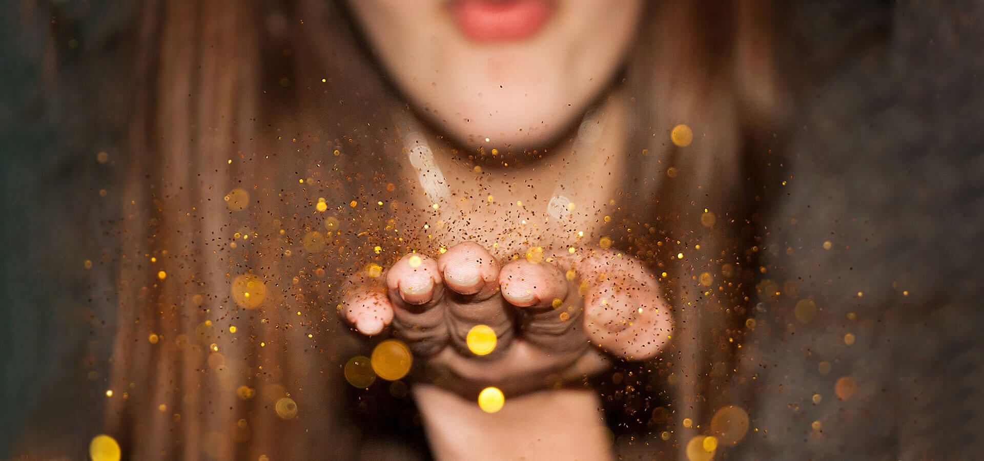 A girl blowing millions of pieces of gold glitter