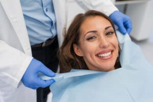 Doctor fixing female patient napkin in modern dental clinic