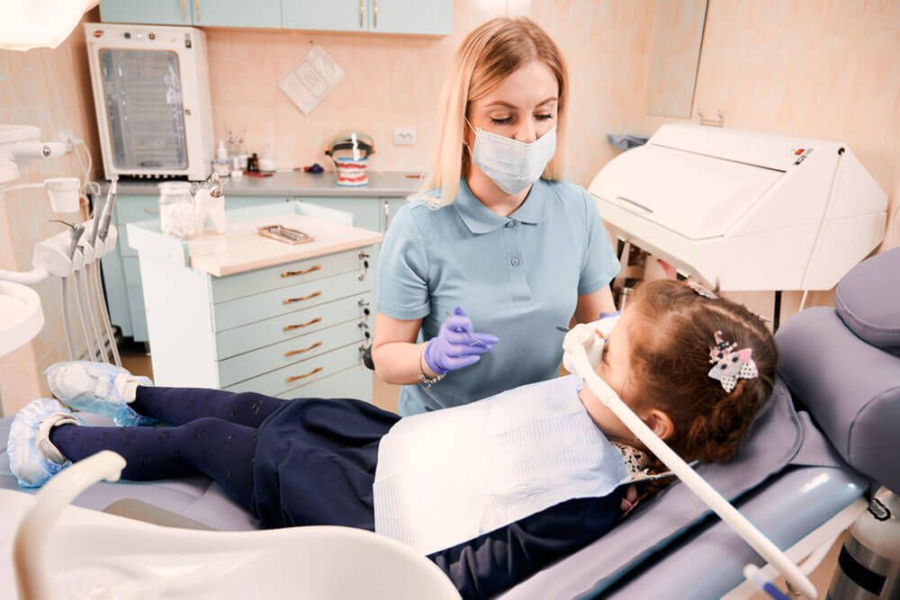 Young woman dentist in medical face mask holding dental instruments