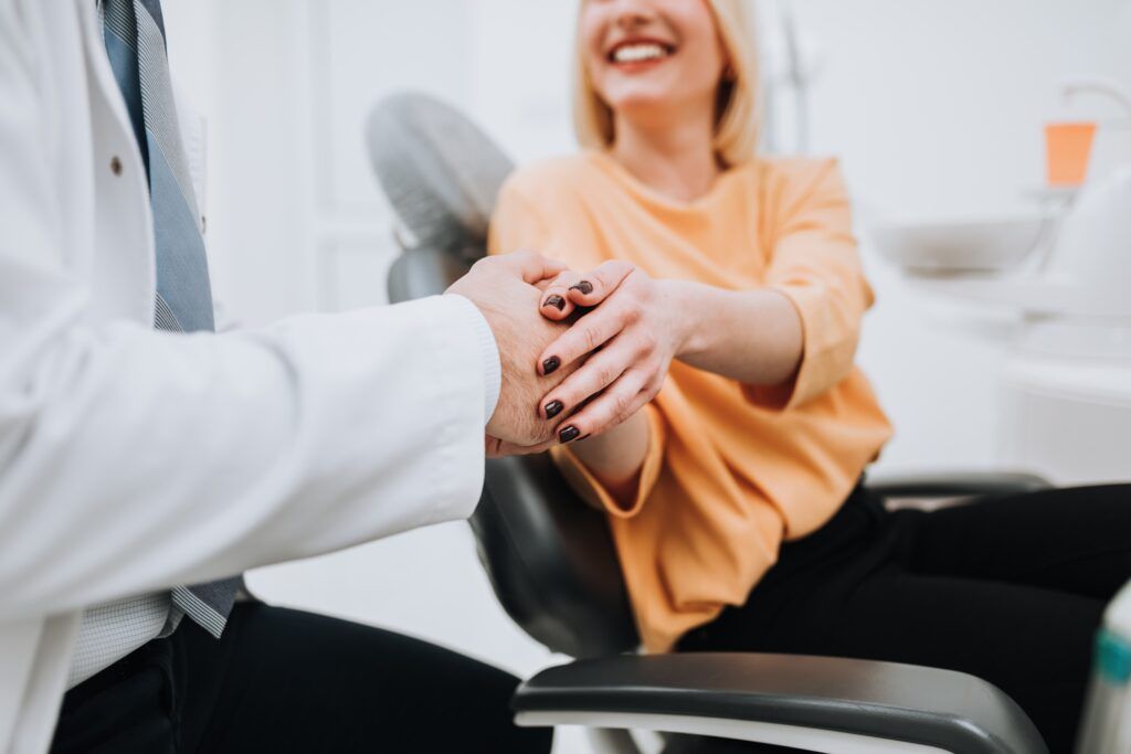 A young blonde woman talks with her dentist about dental treatment.