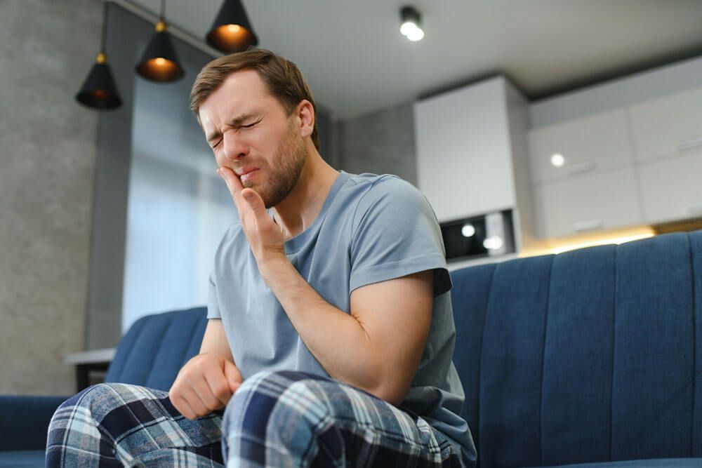 Man with sensitive teeth suffering from pain at home