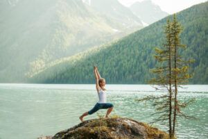 Young woman is practicing yoga at mountain lake