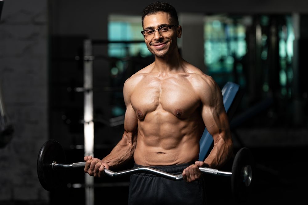 Athlete With Gynecomastia Breasts Problem Working Out Biceps In A Gym