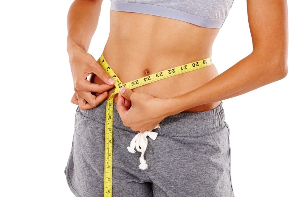 Measuring tape, fitness and tummy of woman in studio for weightloss, exercise and body goals