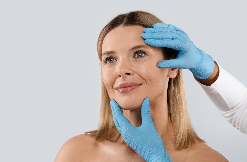 Doctor hands wearing gloves drawing holding female patient head, closeup