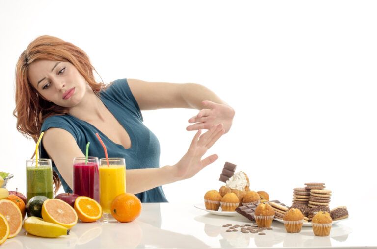 Woman choosing between fruits, smoothie and organic healthy food against sweets, sugar, lots of candies, unhealthy food
