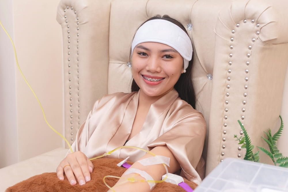 A female patient undergoing a Glutathione IV infusion therapy session at an aesthetic clinic. Also known as a Gluta IV drip.