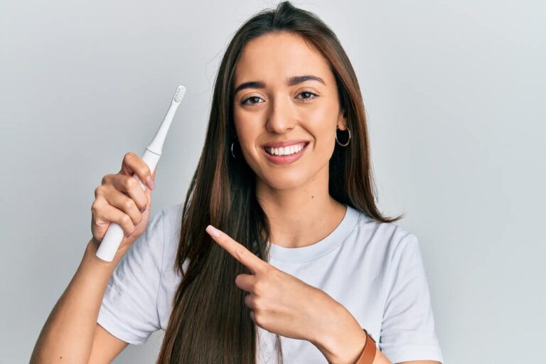 Young hispanic girl holding electric toothbrush
