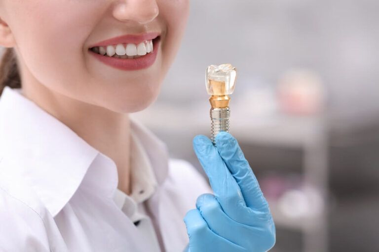 Dentist holding educational model of dental implant indoors