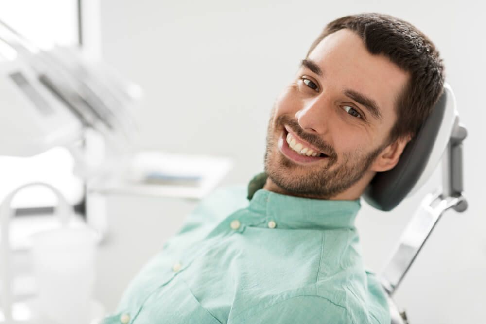 happy smiling male patient on chair at dental clinic