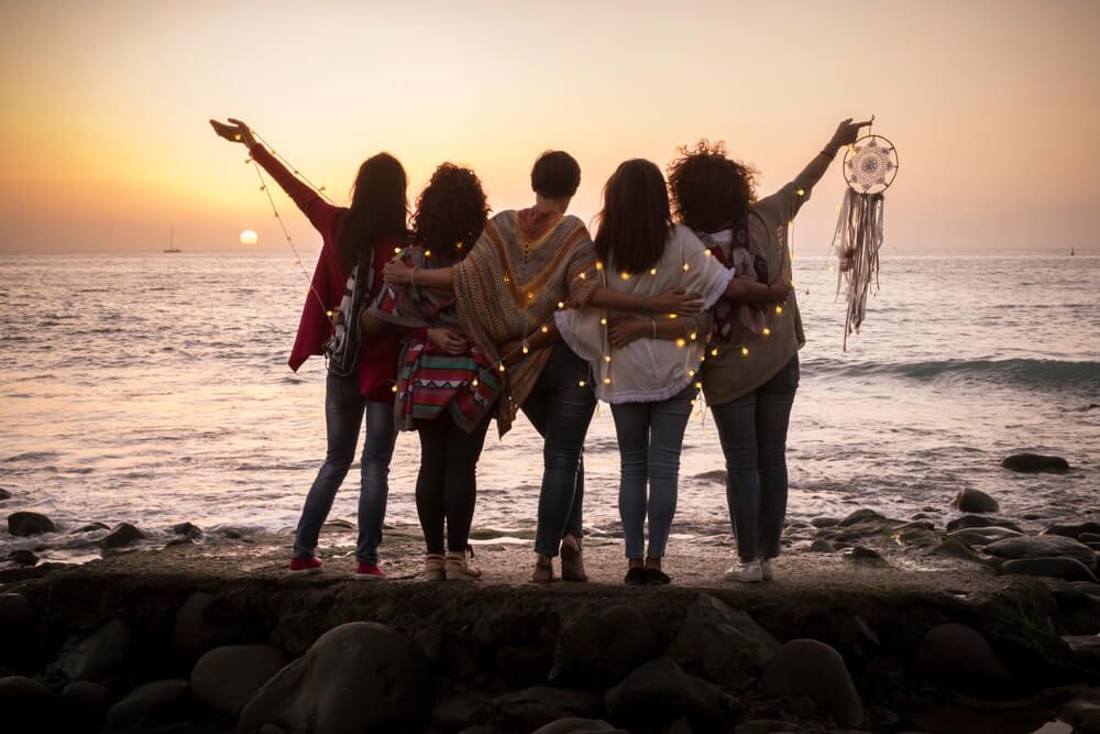 Dreaming image with group of females friends hug each other all together looking the sunset for friendship and love concept