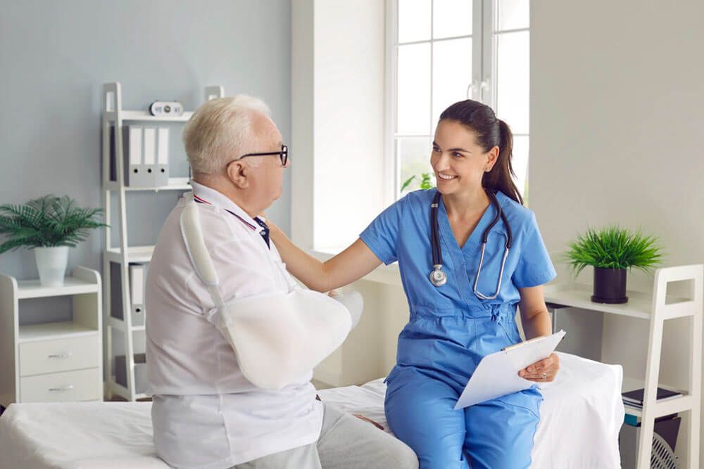 Smiling doctor supporting elder patient with arm injury