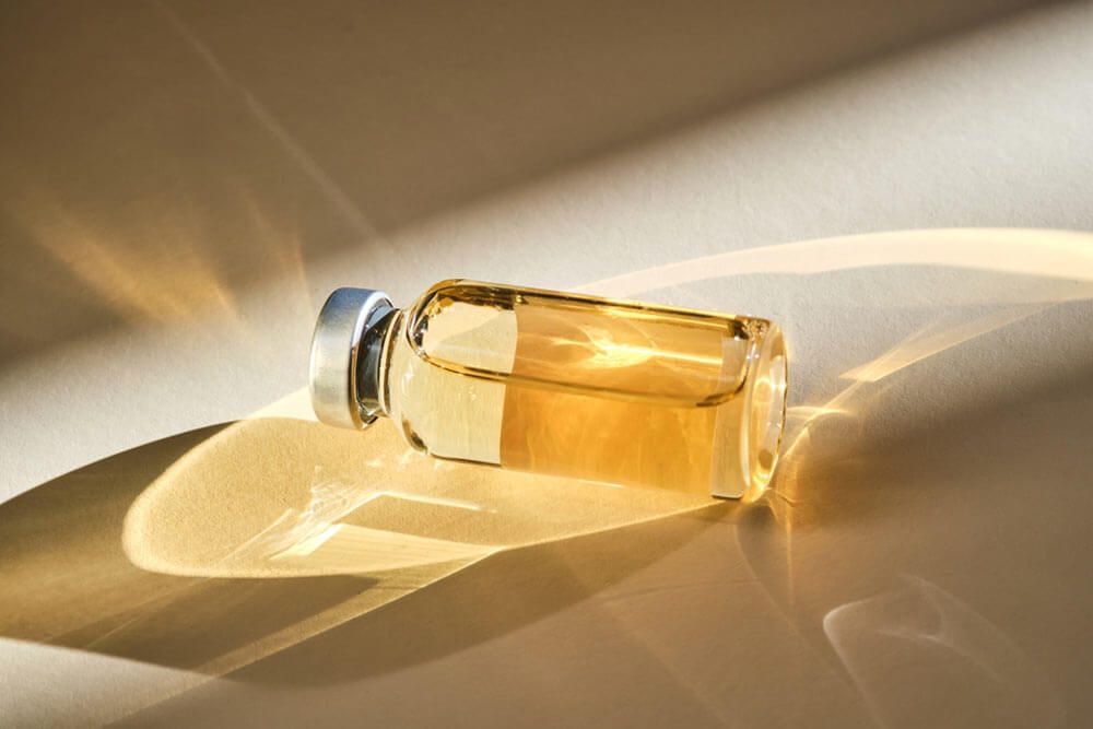 Injection vial with medicinal product in sunlight on beige background.