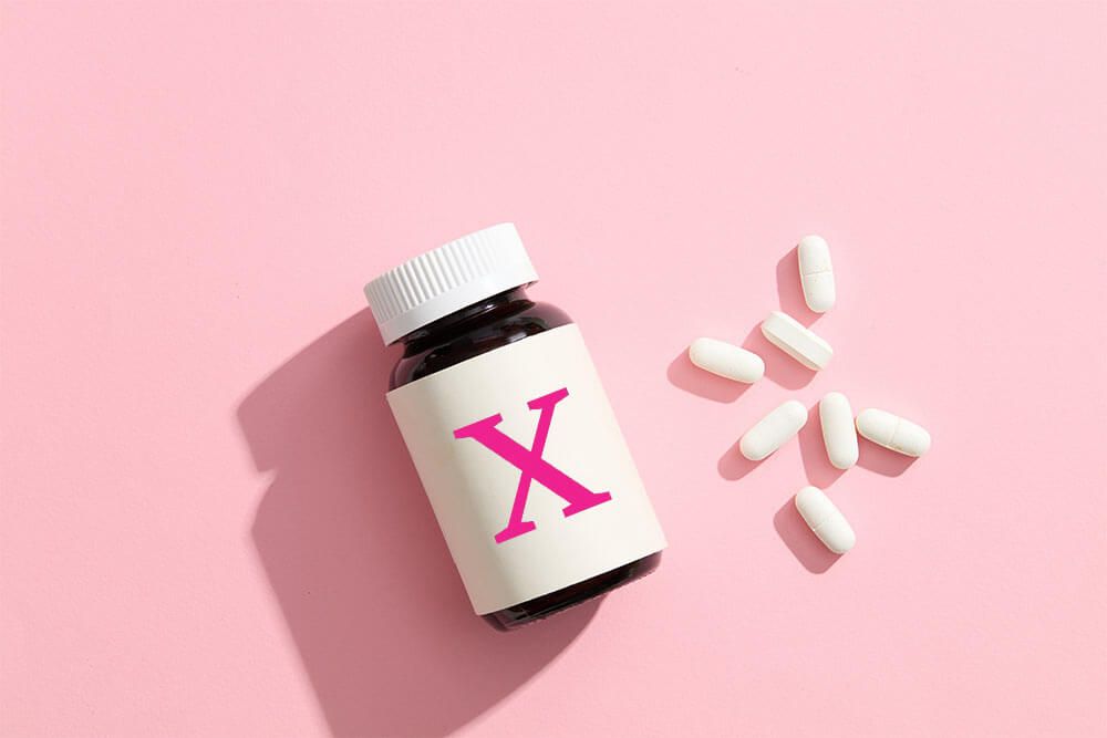 An unlabeled medicine bottle, accompanied by several white pills on a pink background