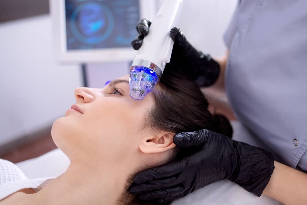 Microneedle RF lifting procedure. Hardware cosmetology. Beautician conducts a facial rejuvenation procedure for a brunette woman
