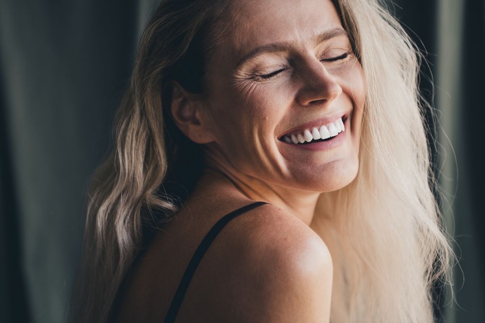 Studio no retouch photo of dreamy positive lady dressed lingerie accepting her age isolated khaki textile background