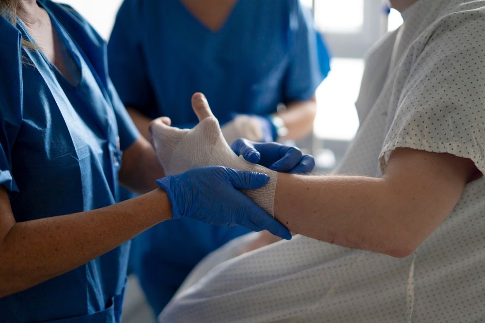 Medical professional providing care and bandaging a patient's hand, ensuring proper wound healing and support