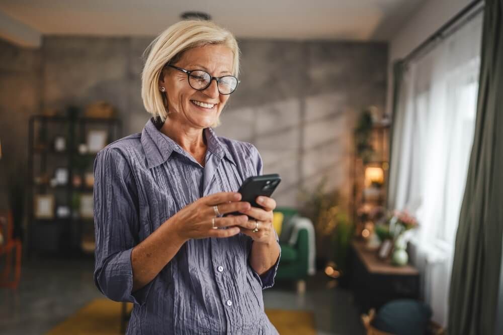 Portrait of mature woman stand and use mobile phone at home