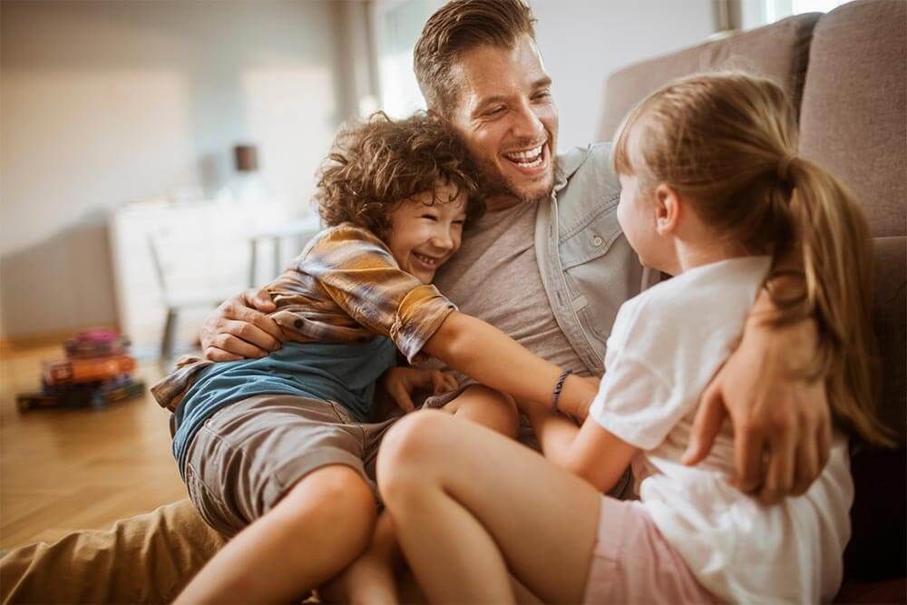 Happy father hugging two kids at home