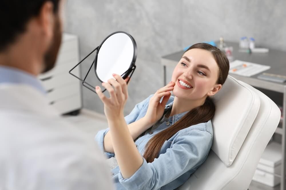 Young woman looking at her new dental implants in mirror