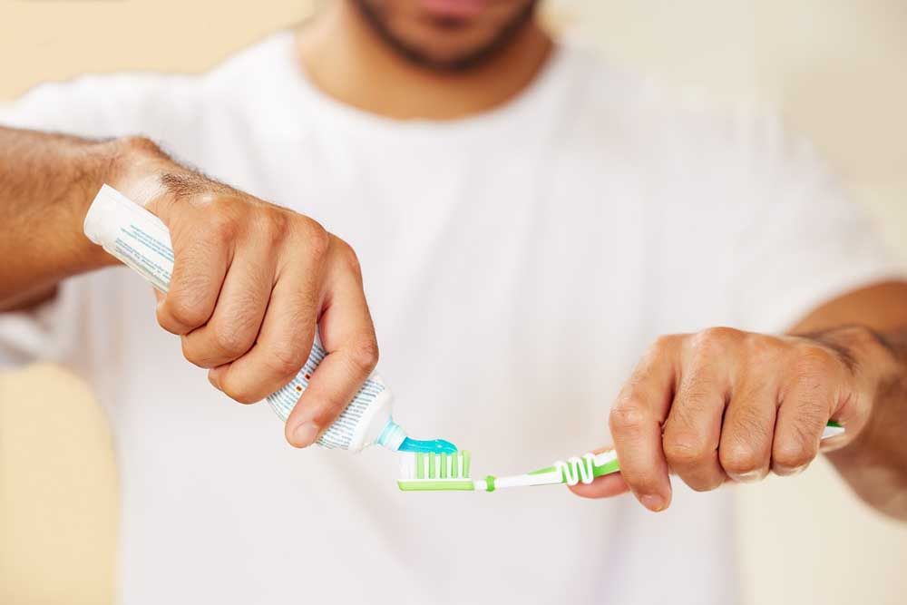 a man putting toothpaste on his toothbrush.