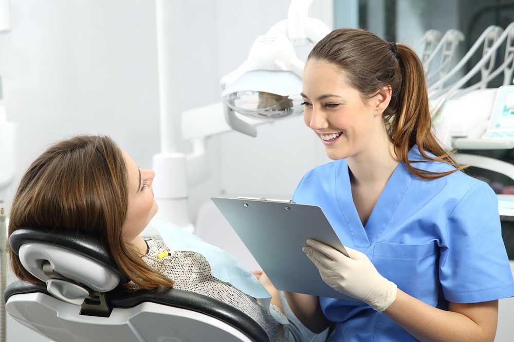 Dentist holding a medical history asking information to a patient