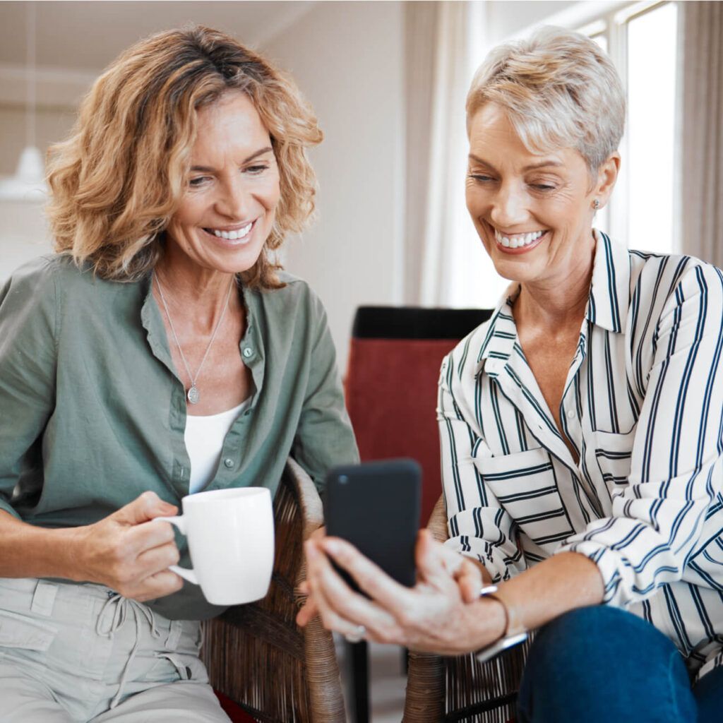 Shot of two female friends drinking coffee while using a digital tablet.