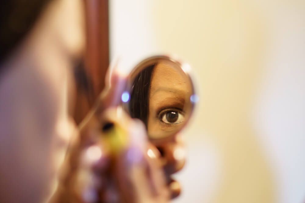 young woman making up looking in mirror reflection