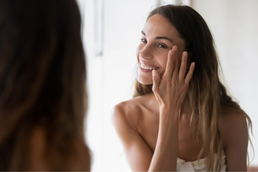 Smiling girl in bath towel look in mirror