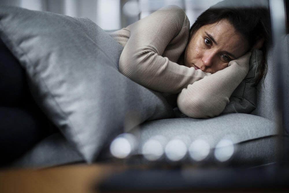 Depressed woman laying on couch