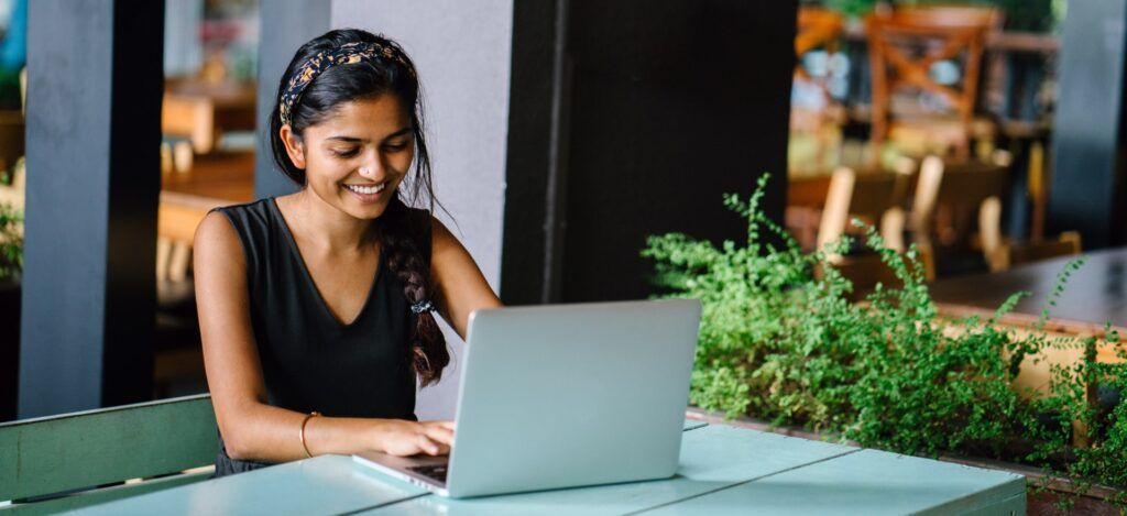 Attractive indian asian female sitting alone at a desk in a cafe