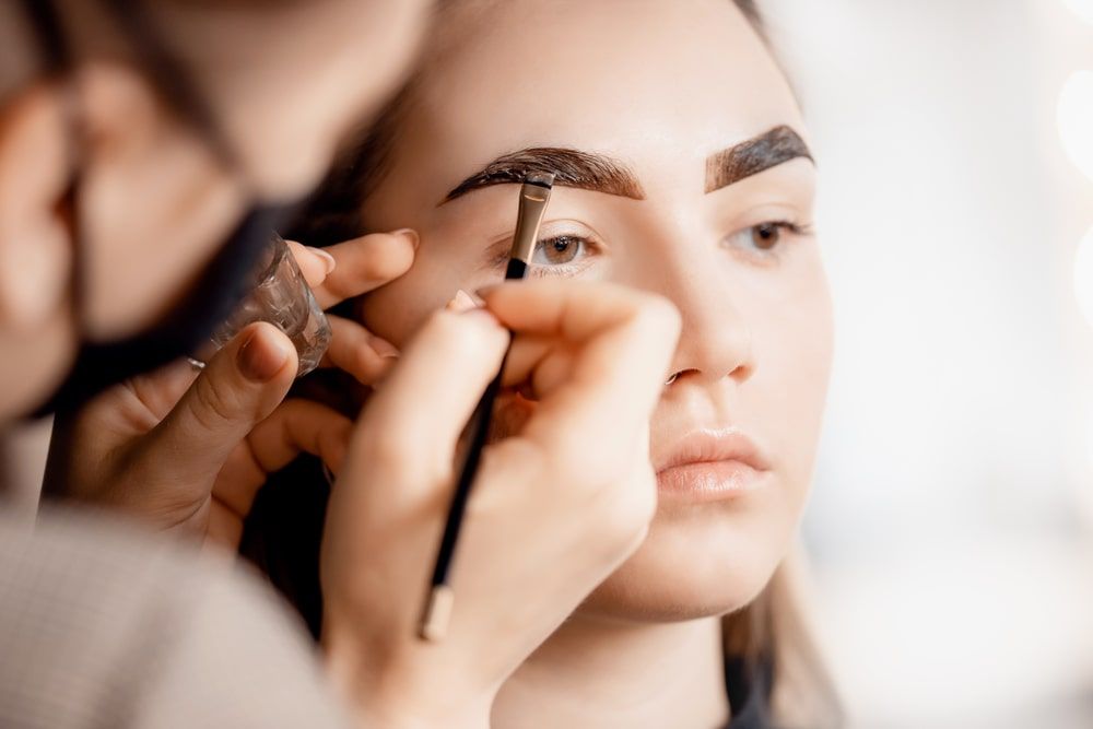 Eyebrow tint, master correction of brow hair women in beauty salon.