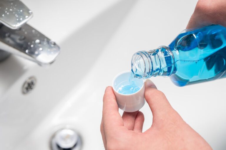 Hand of man Pouring Bottle Of Mouthwash Into Cap
