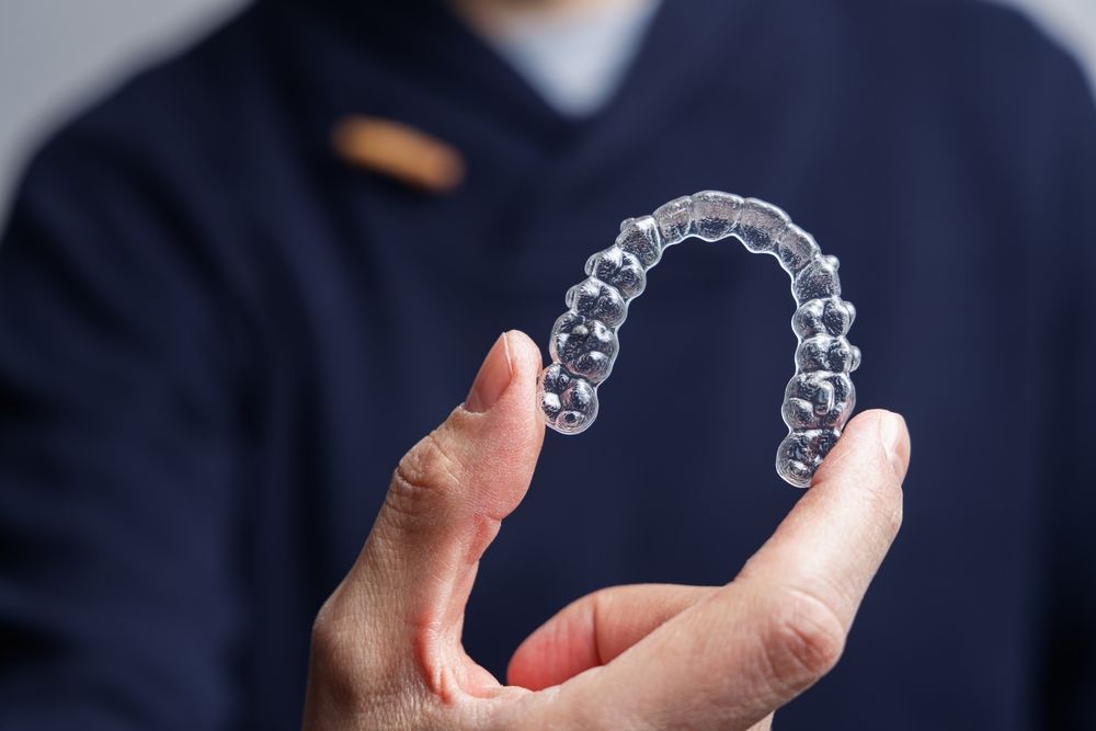 A person holding up an Invisalign aligners