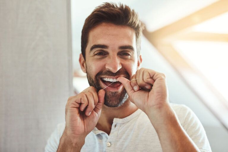 man cleaning teeth with dental floss