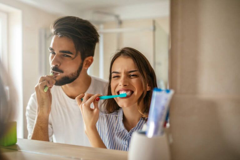 happy couple bonding while brushing teeth in the bathroom