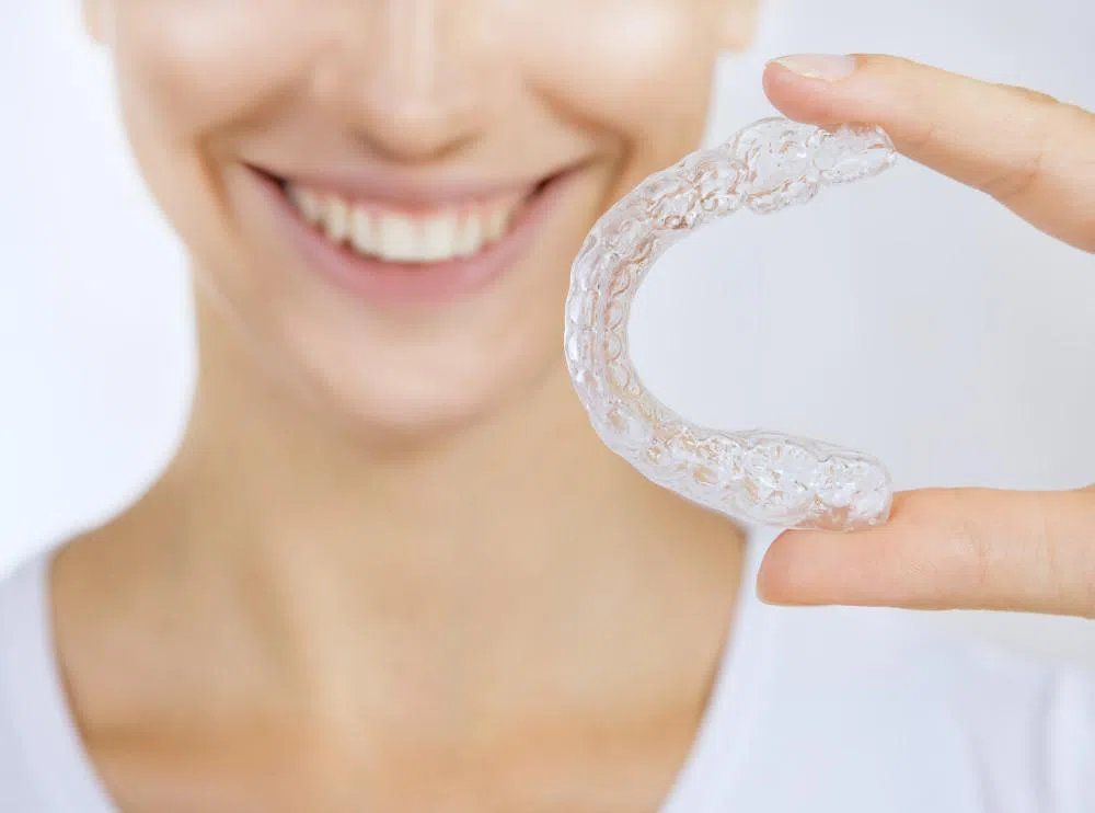 Woman holding Invisalign and smiling