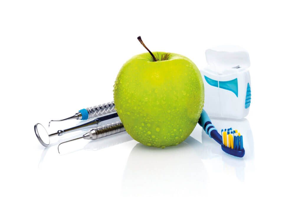 Dentist tools and fresh green apple with water drops