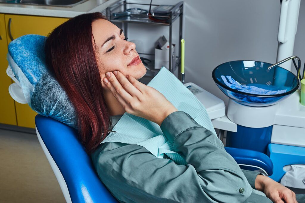 woman with jaw pain sitting in dental chair