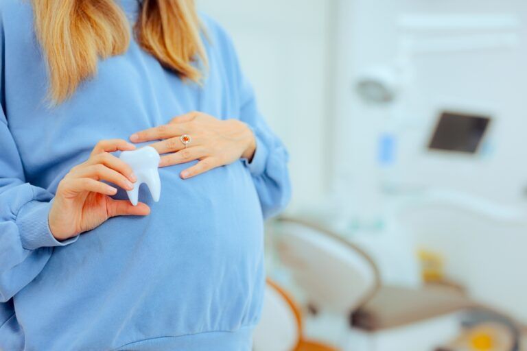 Pregnant Woman Holding a Tooth in a Dental Cabinet