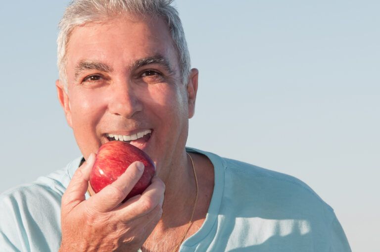 Portrait of a mature man about to eat a red apple