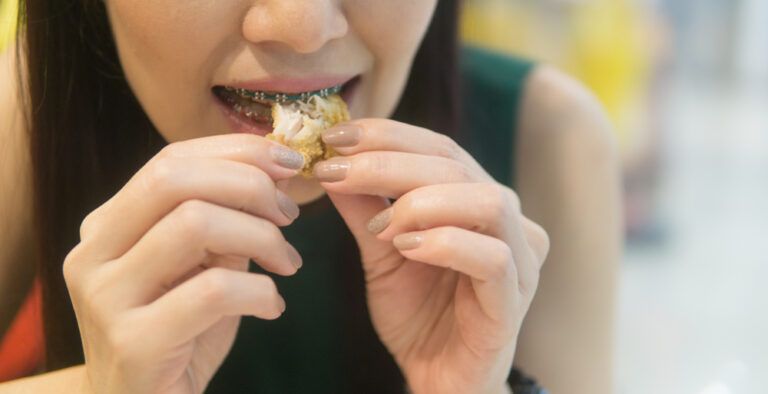 Smiling woman with dental braces enjoy eating