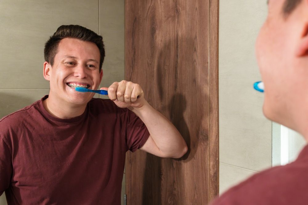 A man maintains his dental health by brushing his teeth, showcasing a daily oral care routine