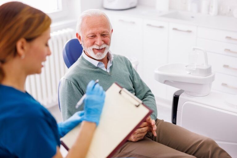 Senior man having dental checkup at dentist office, consulting with doctor about necessary procedures, dentist taking medical records