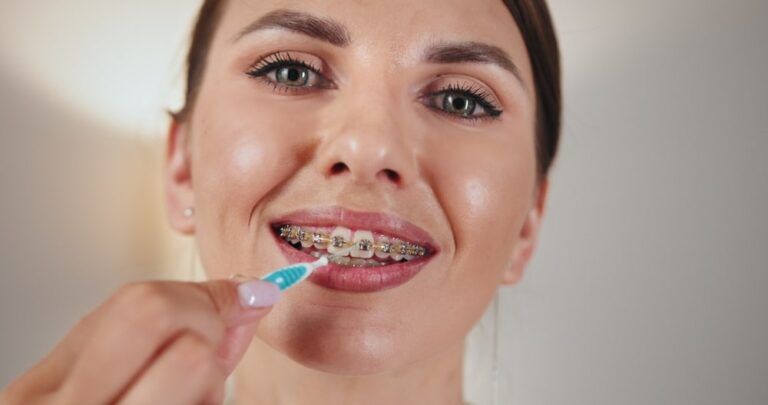 Close-up of young Caucasian woman using dental irrigator to clean braces