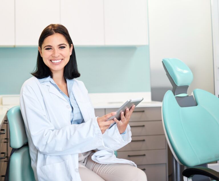 A beautiful, confident female dentist sitting in her doctors rooms