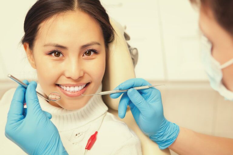 Smiling patient looking at camera while dentist examining it. Dental photo series