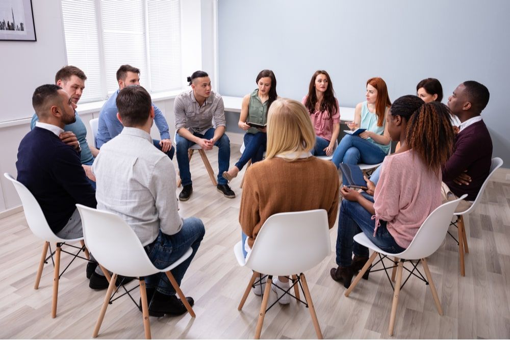 Young Friends Sitting In Circle Having Group Discussion